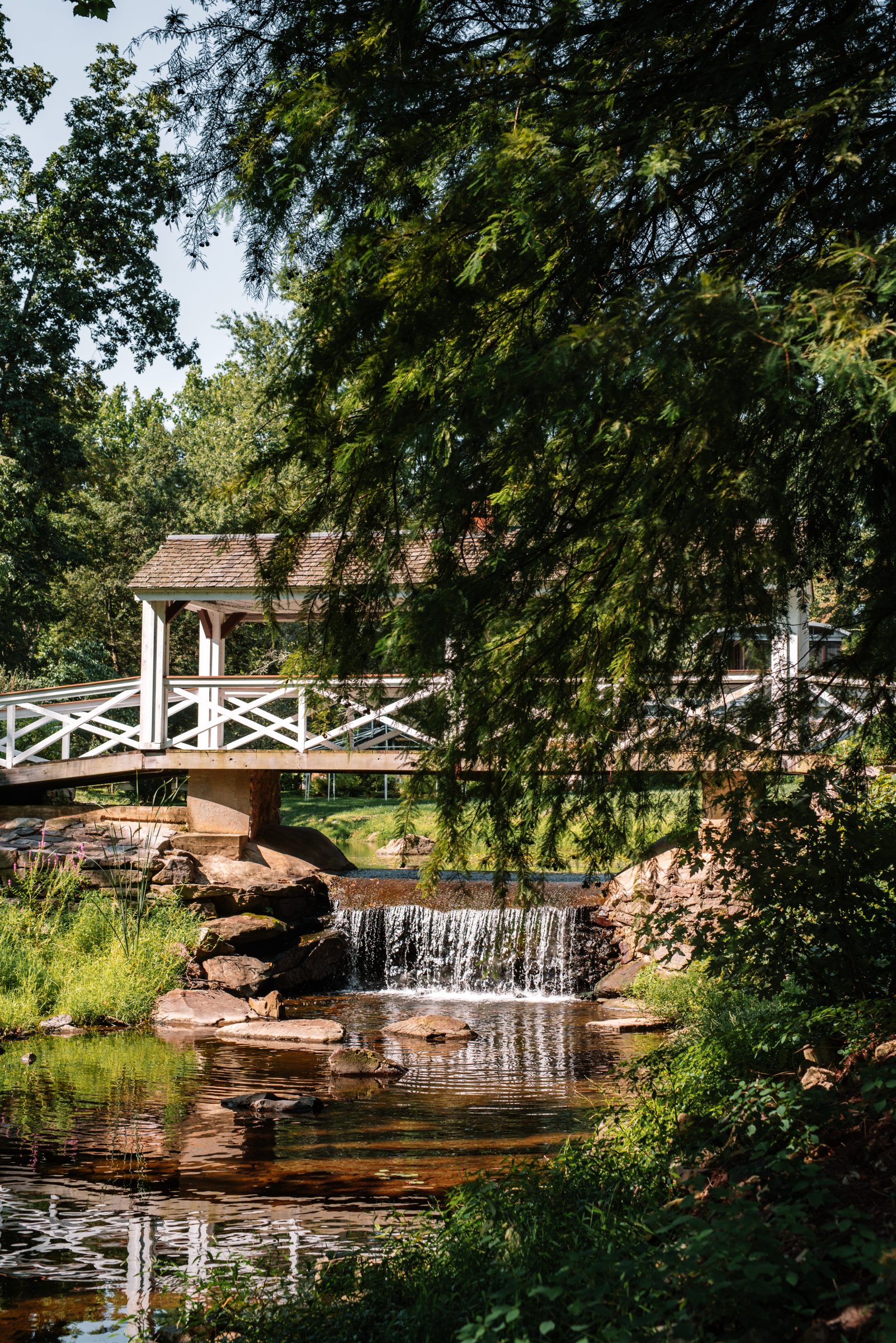 A waterfall spilling beneath the white covered bridge at Brookmill Farm